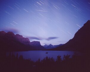 Wild Goose Island A pre-dawn portrait of Wild Goose Island indicated by the warm glow of morning twilight on the distant peaks. The faint vertical bands in the blue sky are the...