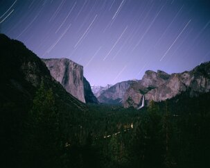 Yosemite Valley by Starlight The light of a setting crescent moon illuminates the famous valley. El Capitan looms on the left, a point of light is seen on its face, the flashlight of a...